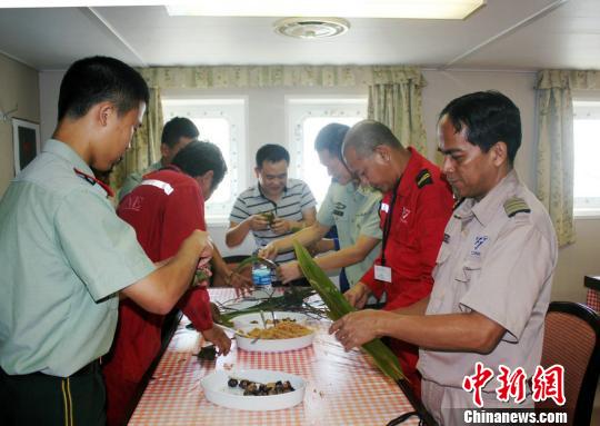 图为漳州边检站官兵与外籍船员一起包粽子。　林志容　摄