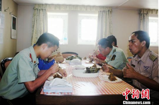 图为漳州边检站官兵与船员一起吃粽子。　林志容　摄