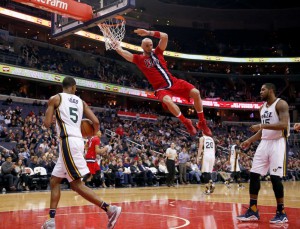 Washington Wizards center Marcin Gortat (13), from Poland, hangs from the rim after his dunk in front of Utah Jazz guard Rodney Hood (5) and forward Derrick Favors during the first half of an NBA basketball game Thursday, Feb. 18, 2016, in Washington. ( Photo by Alex Brandon 