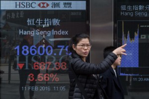 A woman gestures as she walks past a display showing the Hang Sang index outside a bank on the first day of trading of the Lunar New Year in Hong Kong on February 11, 2016. Hong Kong stocks plunged more than four percent to a more than three-year low on February 11, leading another sell-off across Asian markets and extending a global rout fanned by worries over the world economy. AFP PHOTO / DALE DE LA REY / AFP / DALE de la REY 