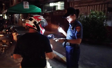 菲律宾政府雷厉风行扫毒，警方报告称，从7月1日迄今 已有1140人被警方击毙。图为一名女警在临检站查验摩 托车骑士身份，查看是否藏有毒品。