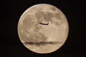 A silhouetted airplane flies past a 'supe rmoon' over New York