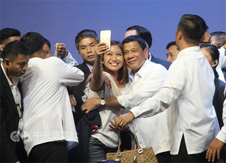 菲律宾总统杜特地赴星国事访问，他16日晚间对旅星菲 社群演讲展现迷人魅力神采。图为一名幸运女粉丝被拉 上台和杜特地（右4）自拍留念。