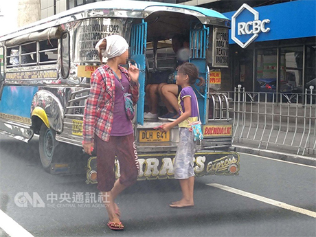 菲律宾一些贫童因没有大人照顾而游荡街头，有些人因此而误入歧途，犯下扒窃丶抢劫及其他罪行。图为两名儿童在菲国马卡蒂市街头向小公车乘客行乞。