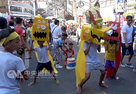 菲律宾孩童以水果箱作头丶水杯为眼，自制狮头，兴致勃勃地表演舞狮。