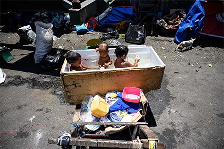 在马尼拉，用废弃的冰箱做临时浴缸，孩子们在里面洗澡。