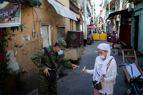 在菲律宾马尼拉的帕赛市，一名军人检查居民的出行许可证。