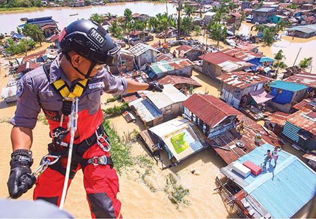 昨天，布拉干省卡仑皮特市的居民仍被洪水围困在他们的屋顶上，纯力救援公司 一位训练有素的救援人员 悬挂在直升机的一侧向居民发出投放救灾包的信号。